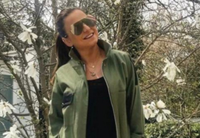 Ania Lewandowska w kurtce khaki stoi przy kwitnącej magnolii Ania Lewandowska w kurtce khaki stoi przy kwitnącej magnolii