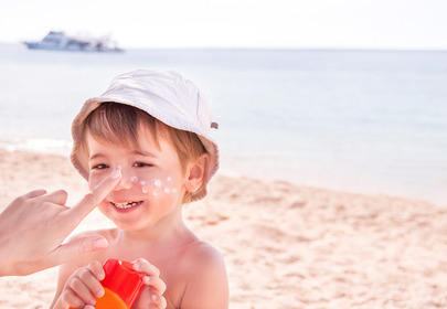 Dziecko na plaży, które ma aplikowany na nos krem przeciwsłoneczny Dziecko na plaży, które ma aplikowany na nos krem przeciwsłoneczny